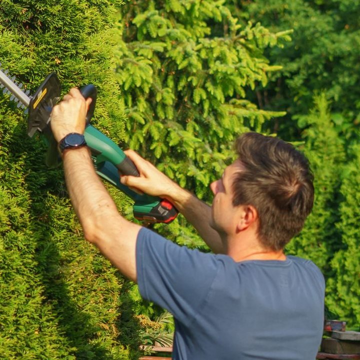 RR Landscaping and Tree Services crew member trimming a hedge